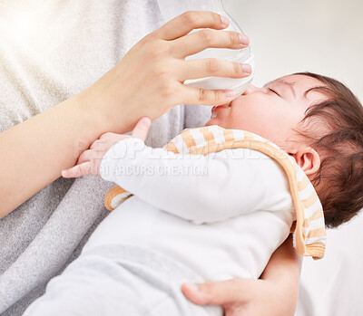 Closeup shot of a cute tired little newborn brunette mixed race baby being bottle fed by unknown single mother. Hispanic baby taking his routine nap while drinking formula milk with his mother at home