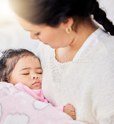Adorable little baby girl feeling warm and safe while sleeping peacefully in her loving mother\'s arms at home. Caring mom holding and rocking her cute daughter to take a cosy and comfortable nap