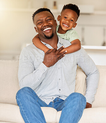 Portrait of an affectionate black man holding his child on a couch. African american father bonding with his son at home. Black single dad laughing and having fun with his happy boy on a sofa