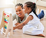 African american mother lying on the wooden floor in the lunge at home smiling with her daughter while playing with educational toys. Adorable little girl playing while bonding and spending time with her mom at home while using a abacus to help her kid co
