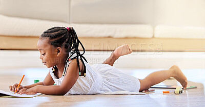 A cute little black african american girl lying on the floor in the lounge at home drawing in a book being creative and learning at the same time. adorable girl having fun, enjoying some creative activities with her colouring pencils