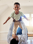 Adorable little african american boy playing in the living room at home with his father. Cute male child smiling and bonding with his dad inside. Having so much fun with his young son