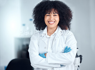 Buy stock photo Portrait of a beautiful young african american woman with an afro wearing a labcoat and gloves while standing with her arms crossed in the laboratory. A mixed race female scientist smiling happily