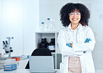 Portrait of proud african american scientist wearing safety goggles in her office. Smiling medical professional with her arms crossed wearing a lab coat in the lab. Powerful scientific expert at work
