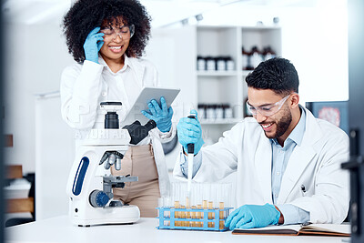 Two mixed race scientists wearing safety equipment while conducting medical research experiments with pipette and test tubes in a lab. Colleagues planning and recording data findings on digital tablet