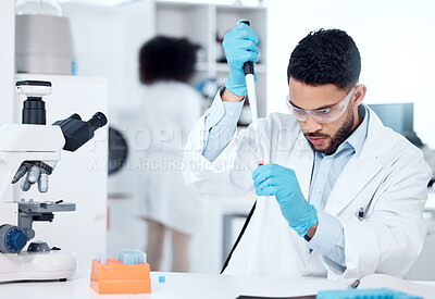 Buy stock photo One mixed race male scientists wearing safety goggles and a lab coat while conducting medical research experiments with pipette and test tubes in a lab. Young hispanic man recording his findings for future investigation and analyzation