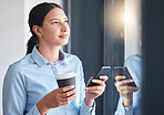 Serious businesswoman thinking, looking at the view from the window while drinking coffee, connected to an online app. Business professional taking a break, texting on her smartphone