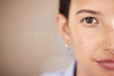 Closeup of mixed race woman\'s eye and face with freckles split in half looking straight ahead at the camera. One female only staring in front of her. Confident woman focused on her goals and vision