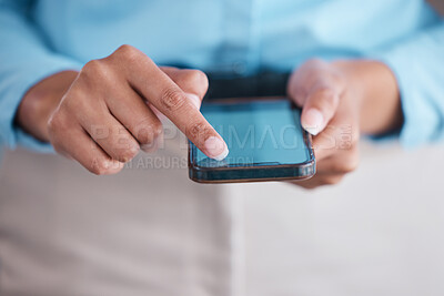 Closeup of female hands holding and and scrolling on smartphone while standing inside a office at work. Business woman typing a message and using social media showing their screen