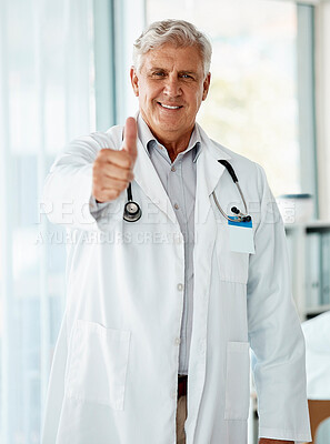 Buy stock photo Happy mature caucasian male doctor smiling while showing a thumbs up working at a hospital alone. One senior man wearing a labcoat standing and expressing support with a hand gesture at a clinic