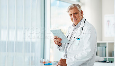 Buy stock photo Happy mature male doctor holding a digital tablet. Smiling senior practitioner using digital tablet to check medical records or results in a hospital