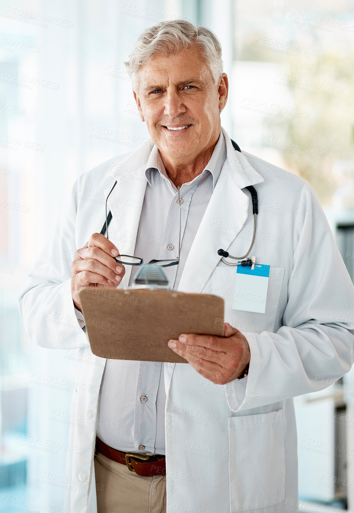 Buy stock photo Confident mature male doctor reading patient records on clipboard in hospital or clinic. One happy senior caucasian man in white coat. Trusted medical physician and practitioner working in healthcare