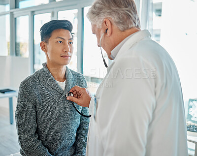 Buy stock photo Asian man getting his chest and heart examined with a stethoscope by caucasian doctor during a routine medical checkup in a hospital or clinic. Physician checking sick patient's vitals for treatment