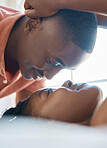 Sensual african american couple bonding and looking eye to eye while spending time together at home. Boyfriend leaning over his girlfriend lying on bed while relaxing together on the weekend