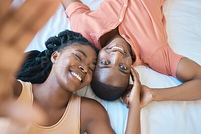 Buy stock photo Portrait of a happy young African American couple smiling and spending the morning in bed together. Black affectionate couple taking a selfie while looking comfortable and relaxed in a bed 