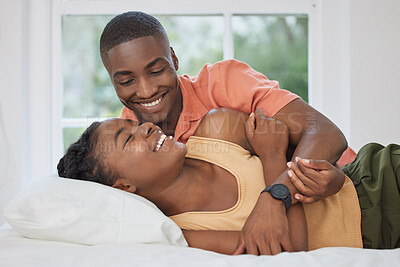 Buy stock photo Young happy and cheerful african american couple bonding and enjoying time together lying on a bed at home. Loving boyfriend and girlfriend relaxing and embracing each other