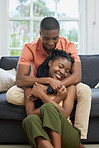 Young african american couple hugging at home, relaxing in the lounge on the couch. Content young couple bonding, embracing affectionately at home. Married couple on romantic date at home being cosy