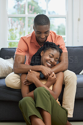 Buy stock photo Young african american couple hugging at home, relaxing in the lounge on the couch. Content young couple bonding, embracing affectionately at home. Married couple on romantic date at home being cosy