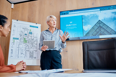 Mature caucasian businesswoman standing and using a tablet while giving a presentation in the boardroom during a meeting with her female only colleagues in a workplace. Our office is going digital