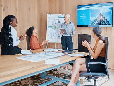 Buy stock photo Mature caucasian businesswoman smiling and standing using a tablet while giving a presentation in the boardroom during a meeting with her female only diverse multiracial colleagues in a workplace
