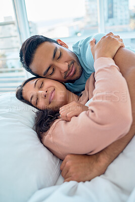 Buy stock photo Young mixed race couple lying in bed together and cuddling early in the morning. Handsome asian man holding his beautiful hispanic wife while he sleeps at home. Feeling safe and protected in his arms