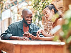 Interracial couple or friends sitting together at cafe while looking at smartphone. Happy young woman showing her boyfriend something on her mobile phone Couple browsing social media or using online banking