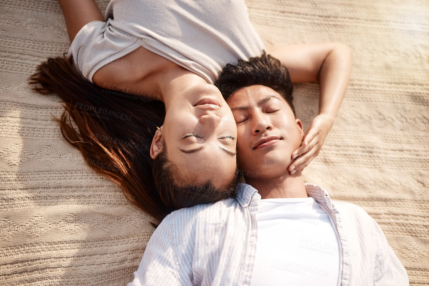Buy stock photo A couple lying on the ground at the beach with their eyes closed  on a sunny