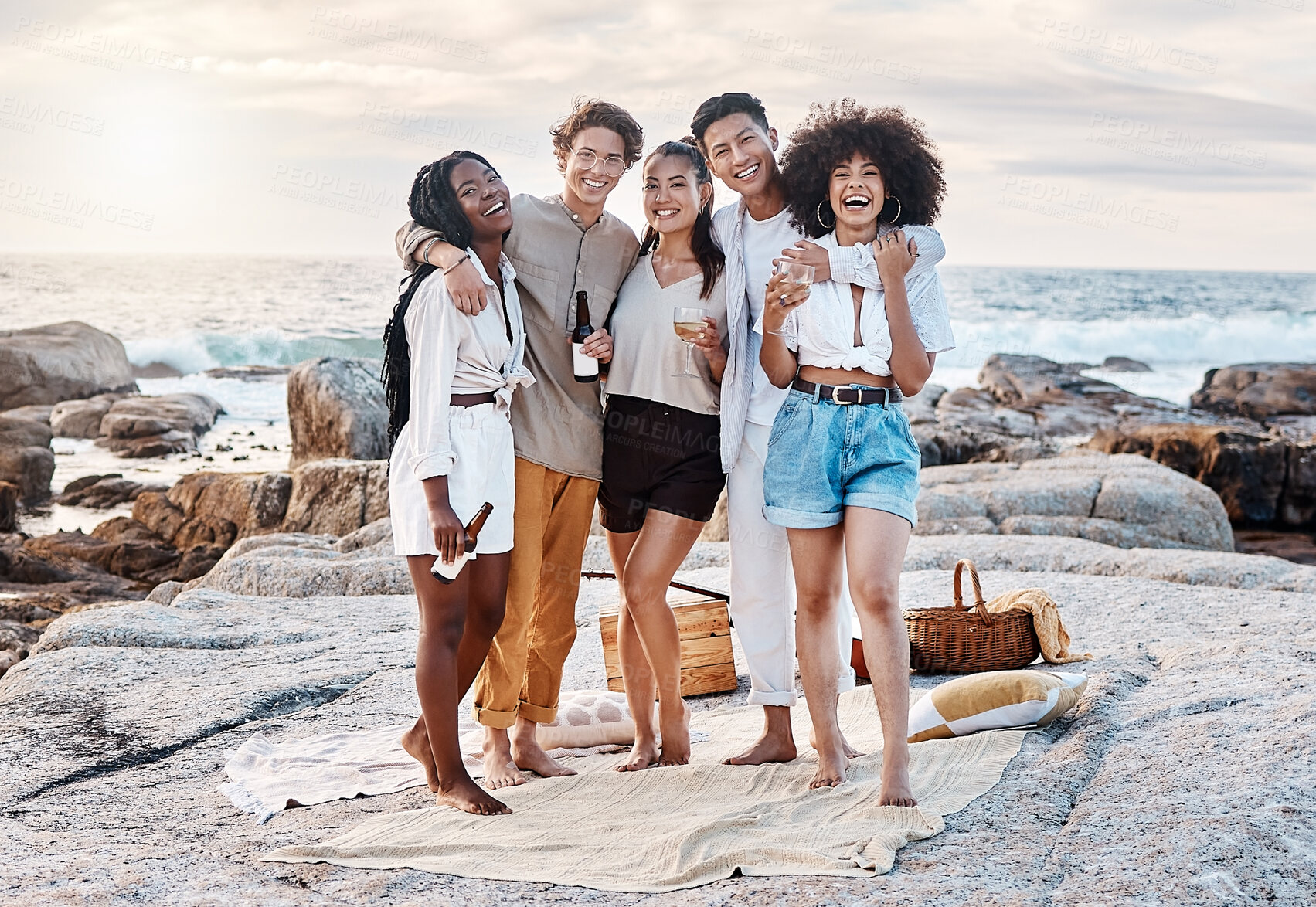 Buy stock photo Portrait of a group of friends enjoying their time together and celebrating with some alcoholic drinks at the beach