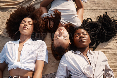 Buy stock photo Young diverse female friends laying on the beach together resting with their eyes closed