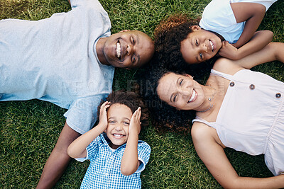 Above view of cheerful african american family lying in a circle. Dad, mom and their two lovely children lying on the grass looking at camera. Little boy and girl having fun with parents at park