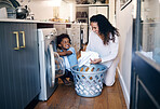 Adorable little African American boy with an afro smiling and faving fun while doing housework with him mother at home. mixed race shot of a cute child folding laundry with his mom 