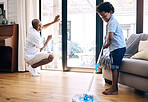 Mature african american dad and his young little son doing housework in the lounge at home. Black man and his boy having fun while cleaning their home together. Black boy and his dad cleaning 