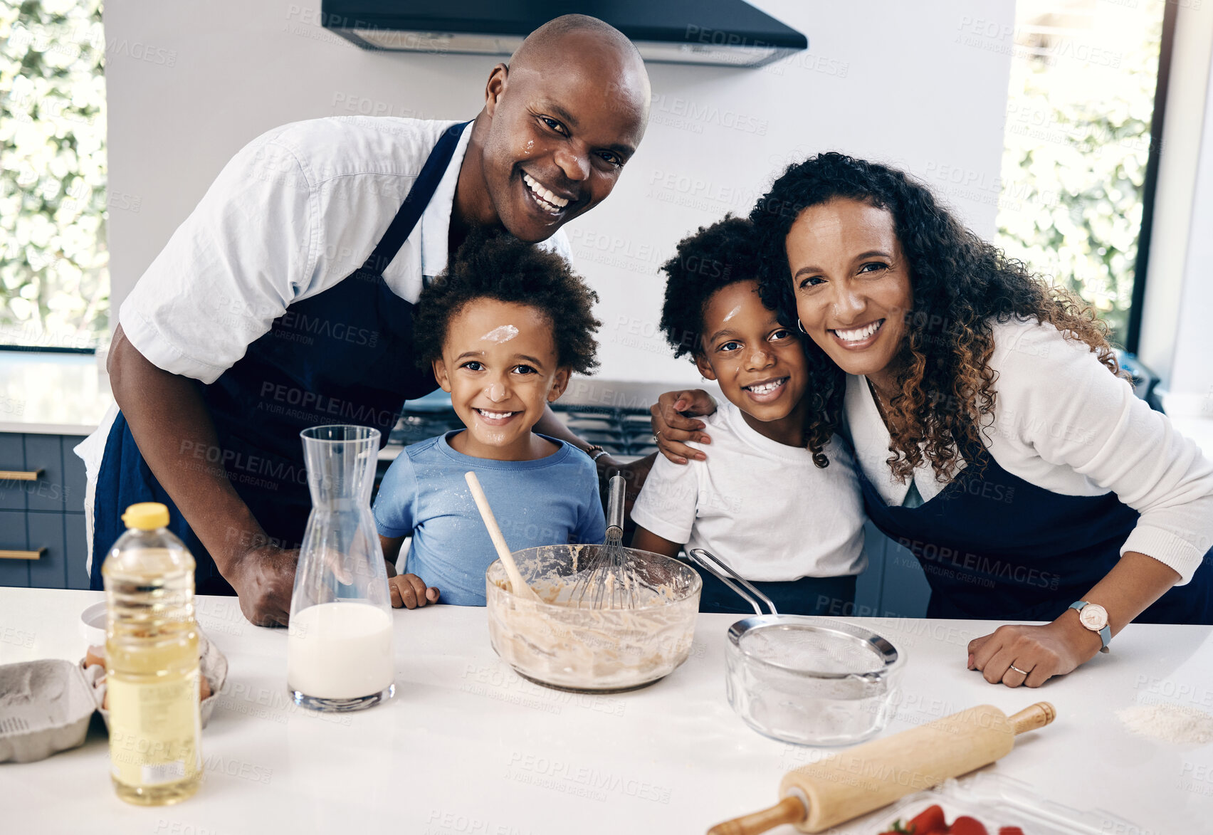 Buy stock photo Portrait of cheerful african american family baking together at home. Happy couple and their two sons having fun while mixing ingredients in their kitchen. Baking is a fun family bonding activity