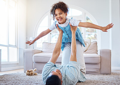 Buy stock photo Adorable smiling mixed race girl bonding with her single father in a home living room. Hispanic man playing games and lifting his daughter into the air. Happy child enjoying a weekend with her parent