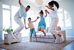 Young parents jumping and playing with their two children at home. Happy hispanic family having fun spending time together. Little boy and girl holding hands and jumping in the air with mom and dad