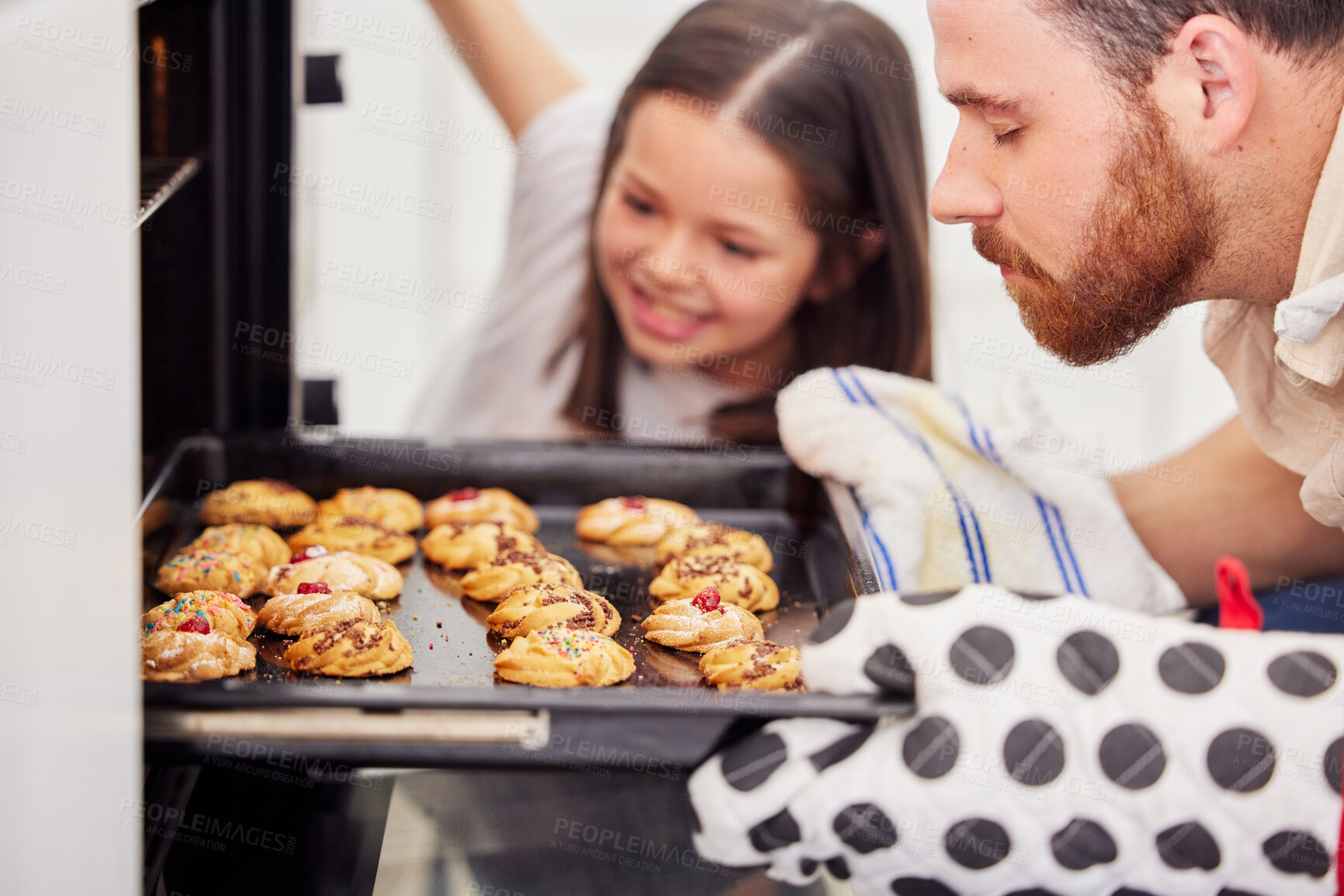 Buy stock photo Father and daughter baking cookies at home. Parent taking baking tray with biscuits out the oven. Single dad and daughter preparing home bakery
