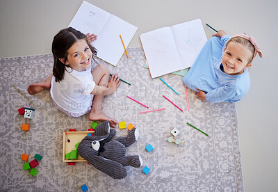 Buy stock photo Adorable little girls drawing with colouring pencils at home from above. Carefree girls bonding while playing together. Sisters doing homework together