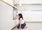 Little girl waiting by the oven for cake to bake. Autistic child watching oven. Excited child waiting to taste or eat