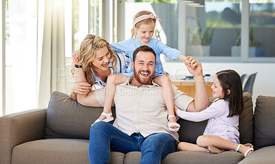 Buy stock photo Carefree caucasian family playing in the living room at home. Active little girls spending time with loving parents. Happy kids bonding with mom and dad
