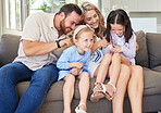 Playful caucasian parents tickling their children while relaxing together on a sofa at home. Carefree little girls spending time with loving parents. Happy family having fun at home