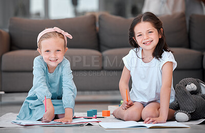 Buy stock photo Two cute little girls having fun while drawing on the floor in the lounge at home together on the weekend. Siblings smiling while doing their homework together. Friends writing in notebooks