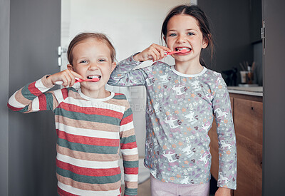 Two caucasian girls in pyjamas brushing teeth together at home. Young sisters practising good hygiene habits. Brush twice daily in the morning and before bedtime to prevent tooth decay and gum disease