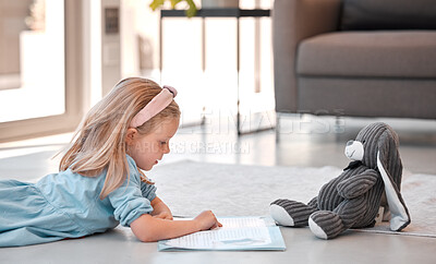 Buy stock photo Little girl reading storybook at home with teddybear. Adorable caucasian girl lying on floor and reading a story to her stuffed animal