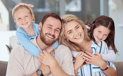 Buy stock photo Happy caucasian family of four smiling while relaxing on a sofa together at home. Carefree loving parents bonding with two cute little daughters. Adorable young playful girls hugging mom and dad