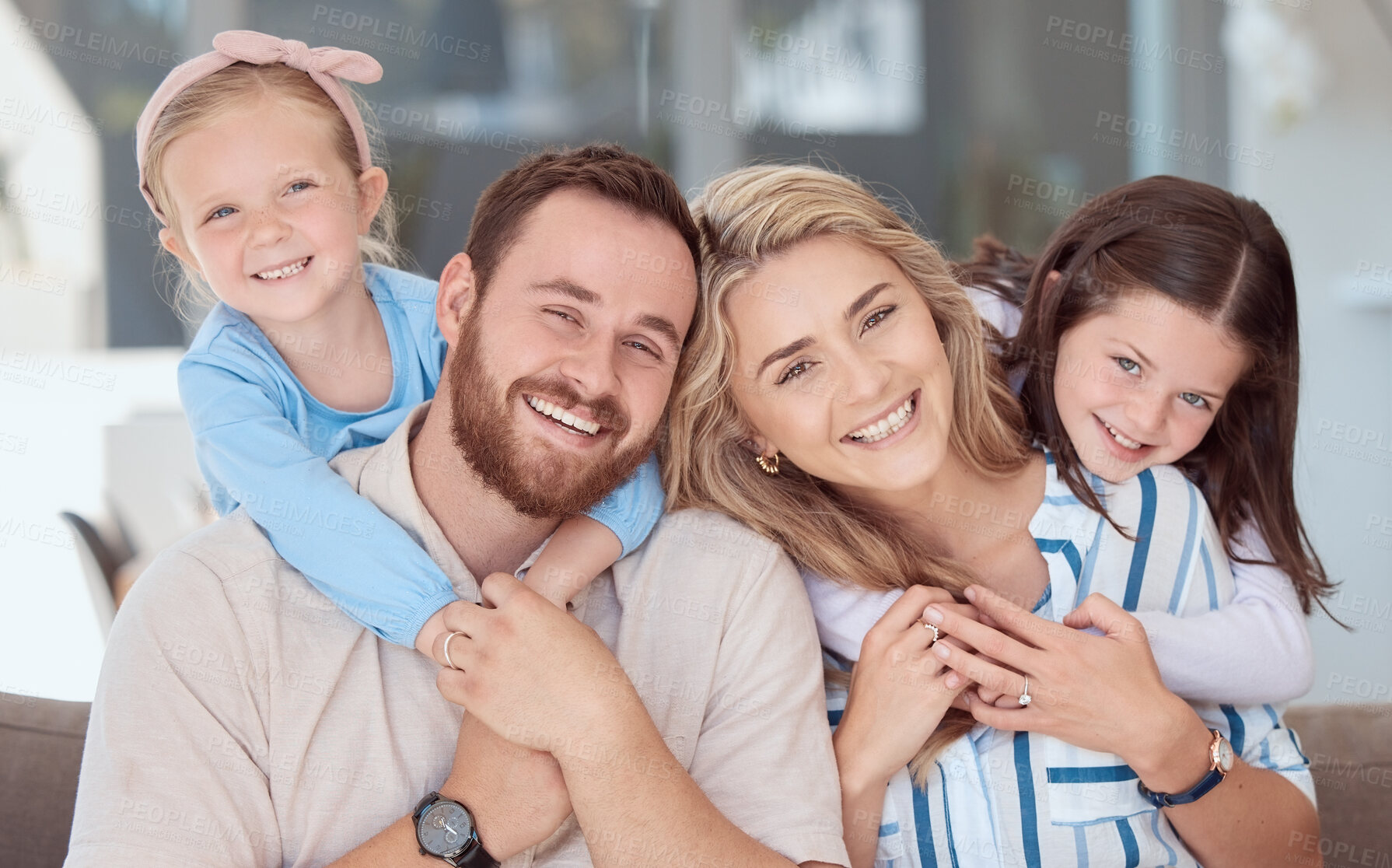 Buy stock photo Happy caucasian family of four smiling while relaxing on a sofa together at home. Carefree loving parents bonding with two cute little daughters. Adorable young playful girls hugging mom and dad
