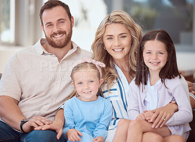 Buy stock photo Portrait of a smiling young caucasian family sitting close together on the sofa at home. Happy adorable girls hugging and bonding with their mother and father on a weekend. Happy couple and daughters