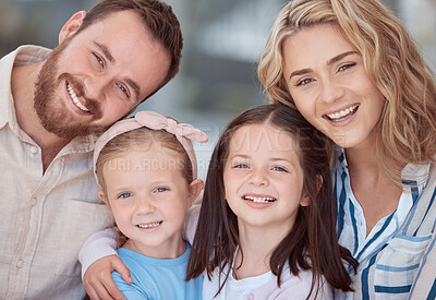 Buy stock photo Portrait of happy young caucasian family sitting together in the living room smiling with healthy teeth at home. Adorable little girls hugging their mom and dad. Carefree parents and their two daughters at home