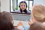 One happy little caucasian girl wearing headphones while appearing on a laptop screen during a video call with friends or relatives. Happy family connected online and talking via webcam. Cheerful kid playing games and chatting to classmates