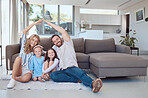 Happy caucasian couple making symbolic roof with hands above cute little daughters while sitting together on floor in living room. Cheerful family in their new home