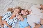 Portrait of happy smiling caucasian family from above relaxing on a carpet floor at home. Carefree loving parents bonding with cute little daughter. Young girl spending quality time with mom and dad